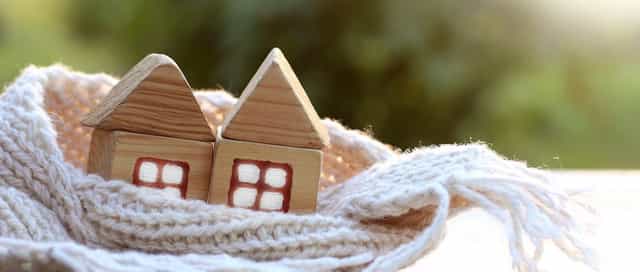 2 Häuser symbolisch für Heizung und Wärme von Steinkühler in Leverkusen in einem Schal eingewickelt.