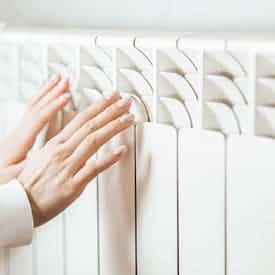 Zwei Hände an einer Heizung nach hydraulischem Abgleich von Steinkühler in Leverkusen.