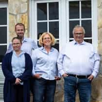 Drei Teammitglieder stehen gemeinsam vor einem Gebäude und lächeln in die Kamera; das Bild vermittelt Zusammenhalt, Erfahrung und Verlässlichkeit im Team eines modernen Handwerksbetriebs – Steinkühler Wasser & Wärme GmbH & Co. KG