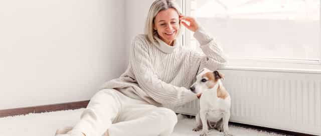 Frau sitzt zufrieden mit ihrem Hund an der warmen Heizung Dank des Licht und Steuerung System von Steinkühler in Leverkusen.